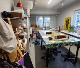 Pokój kreatywny w „Mrowisku” (budynku Towarzystwa Profilaktyki Środowiskowej), w którym dzieci objęte wsparciem mogą wykonywać prace plastyczne. Na zdjęciu na środku pomieszczenia widoczny duży stół i krzesła, przy ścianach regały z kolorowymi materiałami plastycznymi.